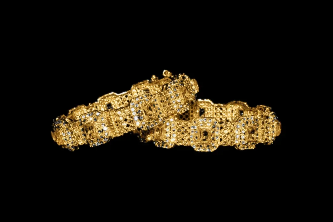 Pair of stone-set gold bangles on dark cloth